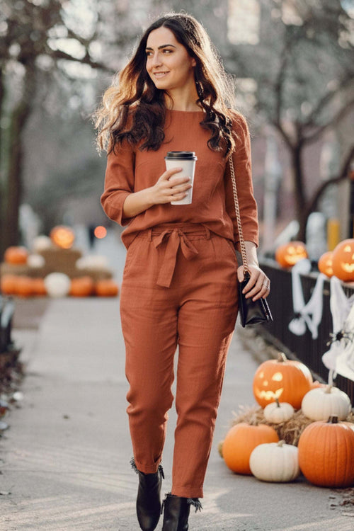 woman wearing rust-colored 100% cotton linen two-piece set walking outdoors with pumpkins around