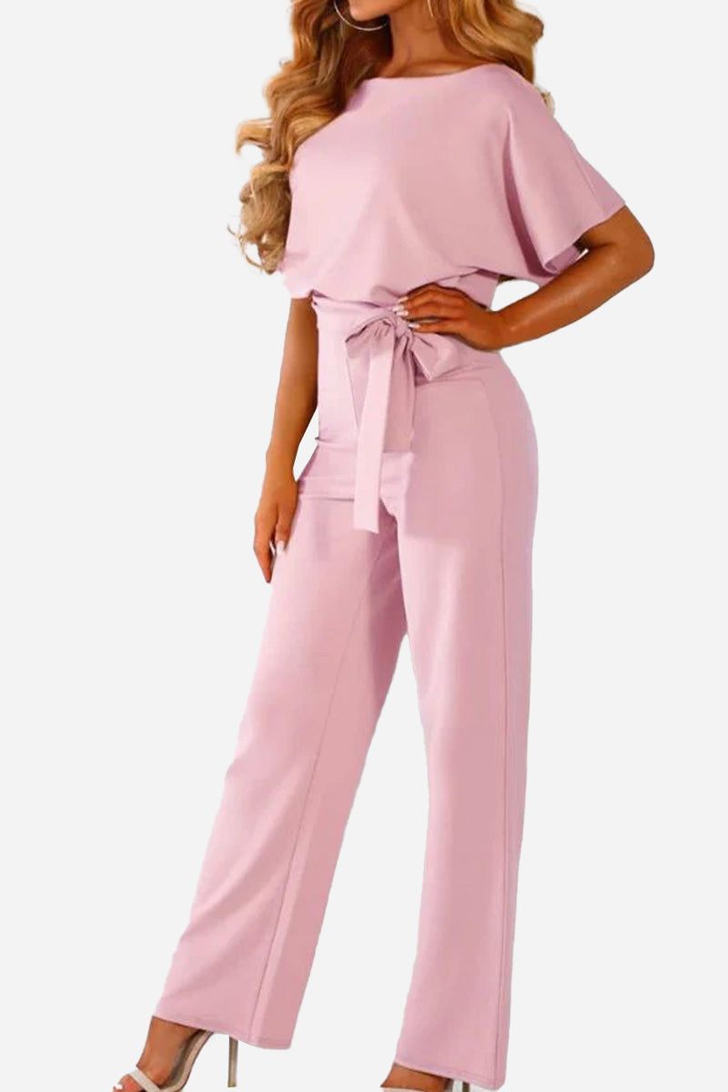 Woman wearing chic short-sleeved wide-leg pink jumpsuit with belt and high waist