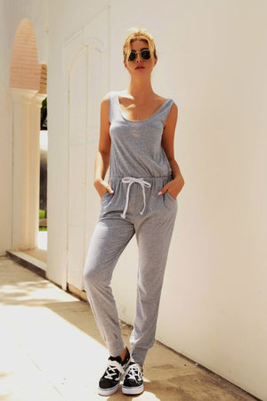 Woman wearing grey comfy sleeveless vest pocket jumpsuit with drawstring waist and sneakers outdoors