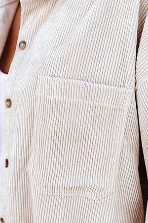 Close-up of beige sleek suede oversized button-down shirt with textured fabric and front pocket detail