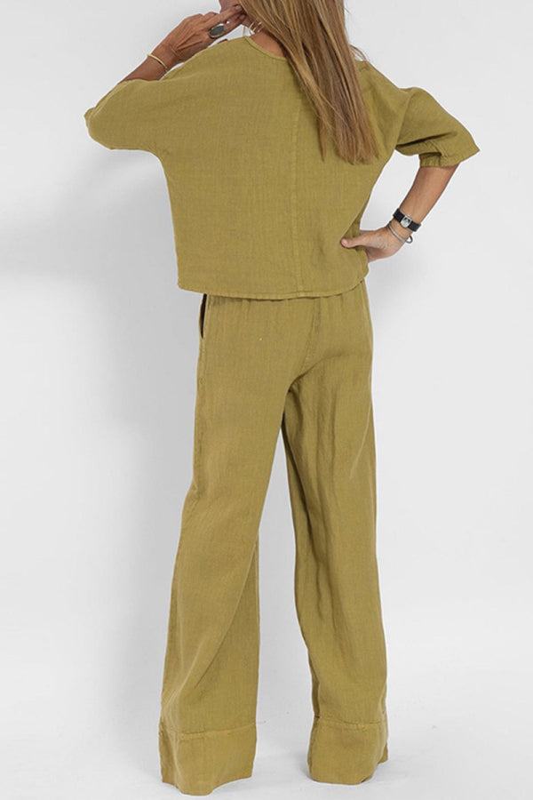 Woman wearing mustard yellow short-sleeved pullover and wide trouser matching set from the Christmas collection, shown from the back