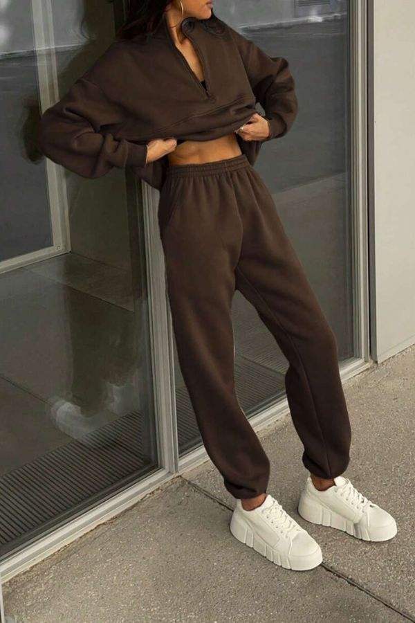 Woman wearing a dark brown cotton-blended two-piece tracksuit with high collar and white sneakers.