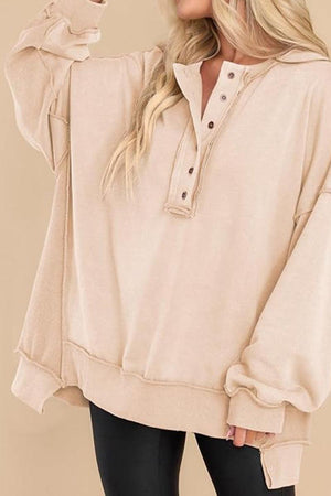 Beige oversized urban sweatshirt with buttoned Henley neckline and slouchy sleeves on model