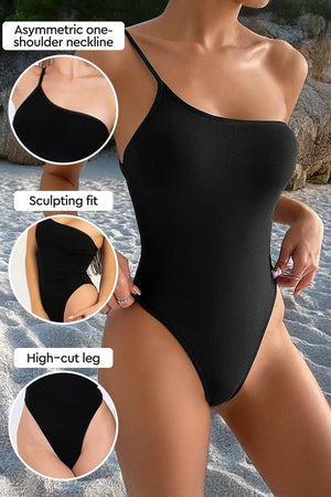 Black asymmetric one-shoulder one-piece swimsuit with high-cut leg and sculpting fit, designed for an even tan without lines.