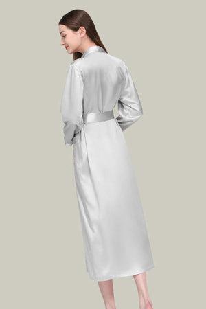 Woman wearing elegant white Mulberry silk nightgown with sash belt and long sleeves, back view