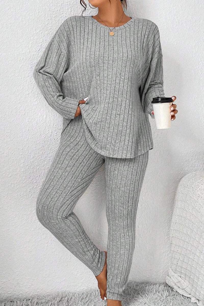 Woman wearing a gray Body Confident Oversized Knit two-piece set holding a coffee cup against a white wall background