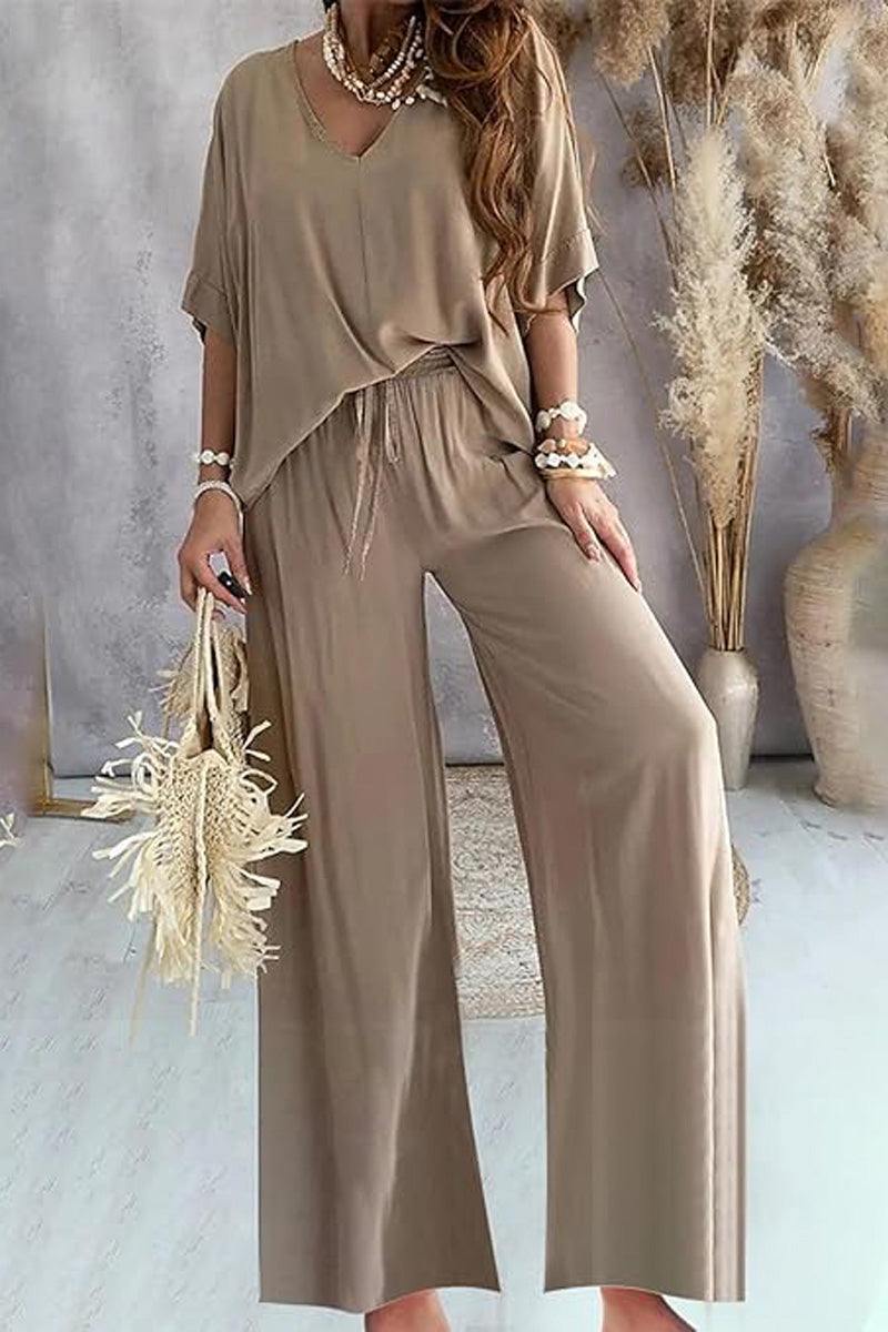 women's casual beige two-piece pantsuit with V-neck top and wide-leg pants styled with bracelets and a woven handbag against a neutral indoor backdrop
