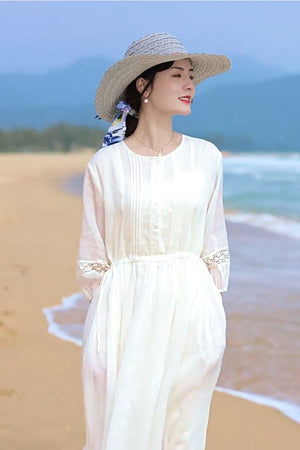 woman wearing white 100 linen coastal shift dress and straw hat on beach