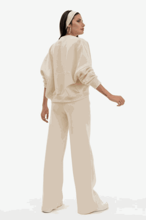 Woman wearing The Voyager Zip Set beige zip-front sweatshirt and wide-leg joggers from back with relaxed fit and pockets