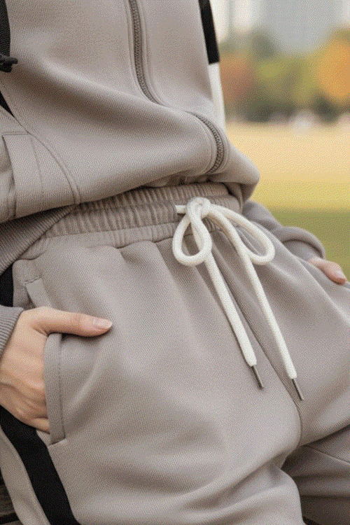 Close-up of beige Comfort in Motion athleisure tracksuit with drawstring waist and hands in pockets