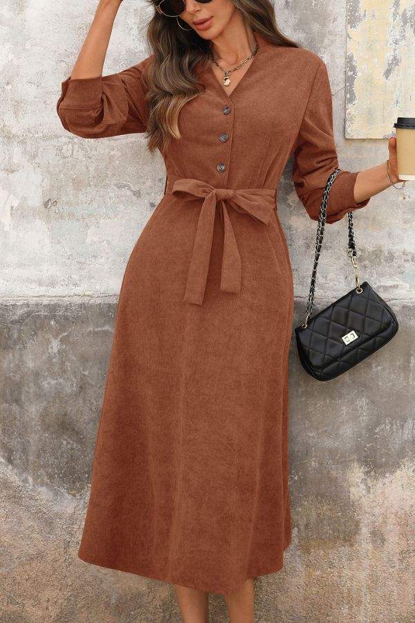Effortlessly polished corduroy tie-waist midi dress in brown with button front and long sleeves, styled with black handbag and coffee cup.