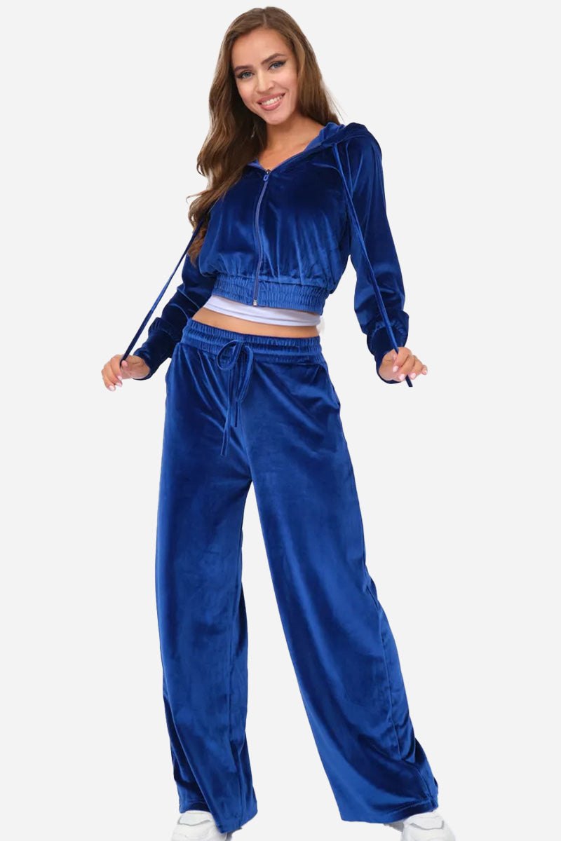Woman wearing modern cropped velour tracksuit in vibrant blue with high-waist drawstring pants and hooded jacket