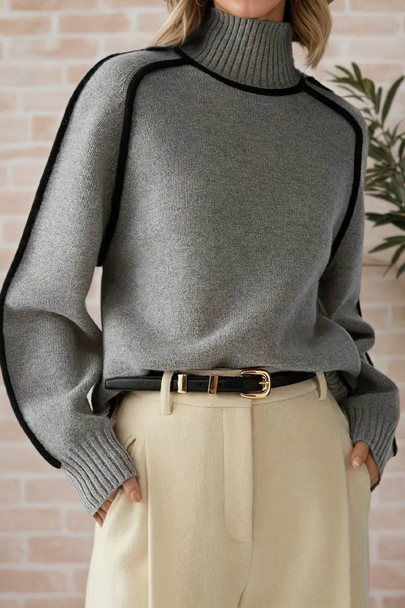 Gray Zero Itch Turtleneck Sweater with black contrast trim and relaxed fit, worn with beige trousers