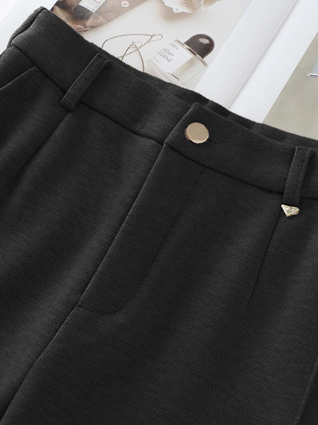 Close-up view of black thermal wool blend trousers with tailored design and gold button closure