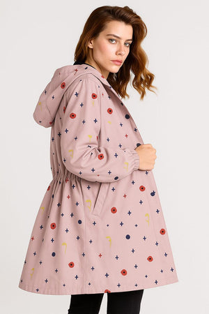 Water-resistant oversized hooded windbreaker jacket with colorful pattern on pink fabric worn by woman