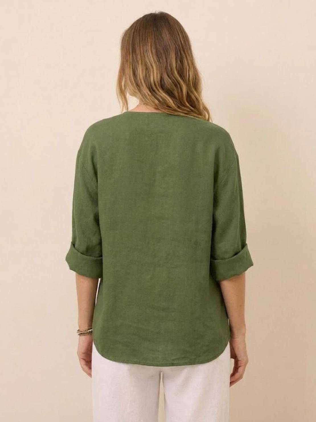 Back view of woman wearing a green pure linen age-defying shirt with rolled sleeves and white pants
