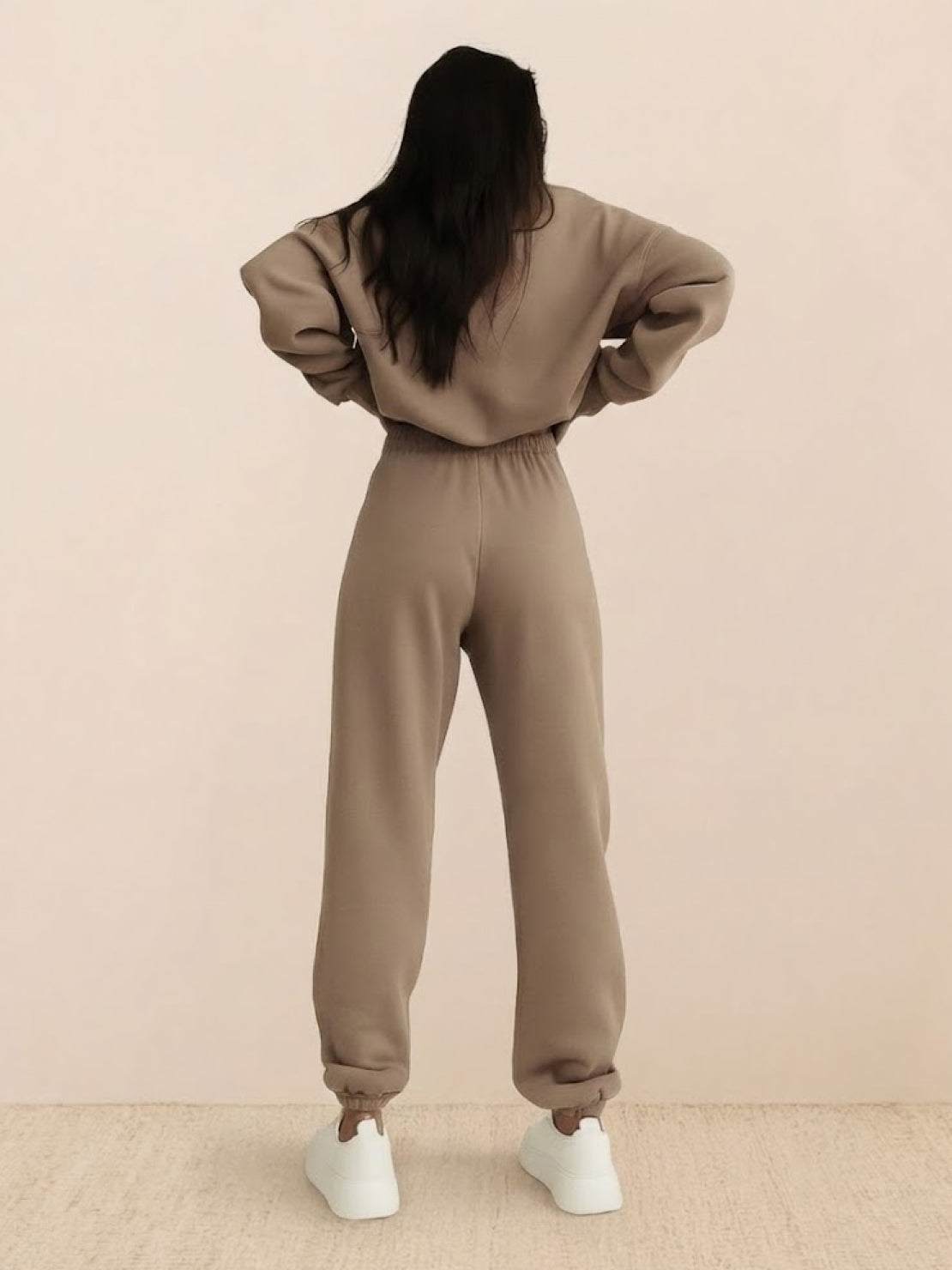 Woman wearing a cotton-blended two-piece tracksuit with high collar and deep zipper in monochrome athleisure style