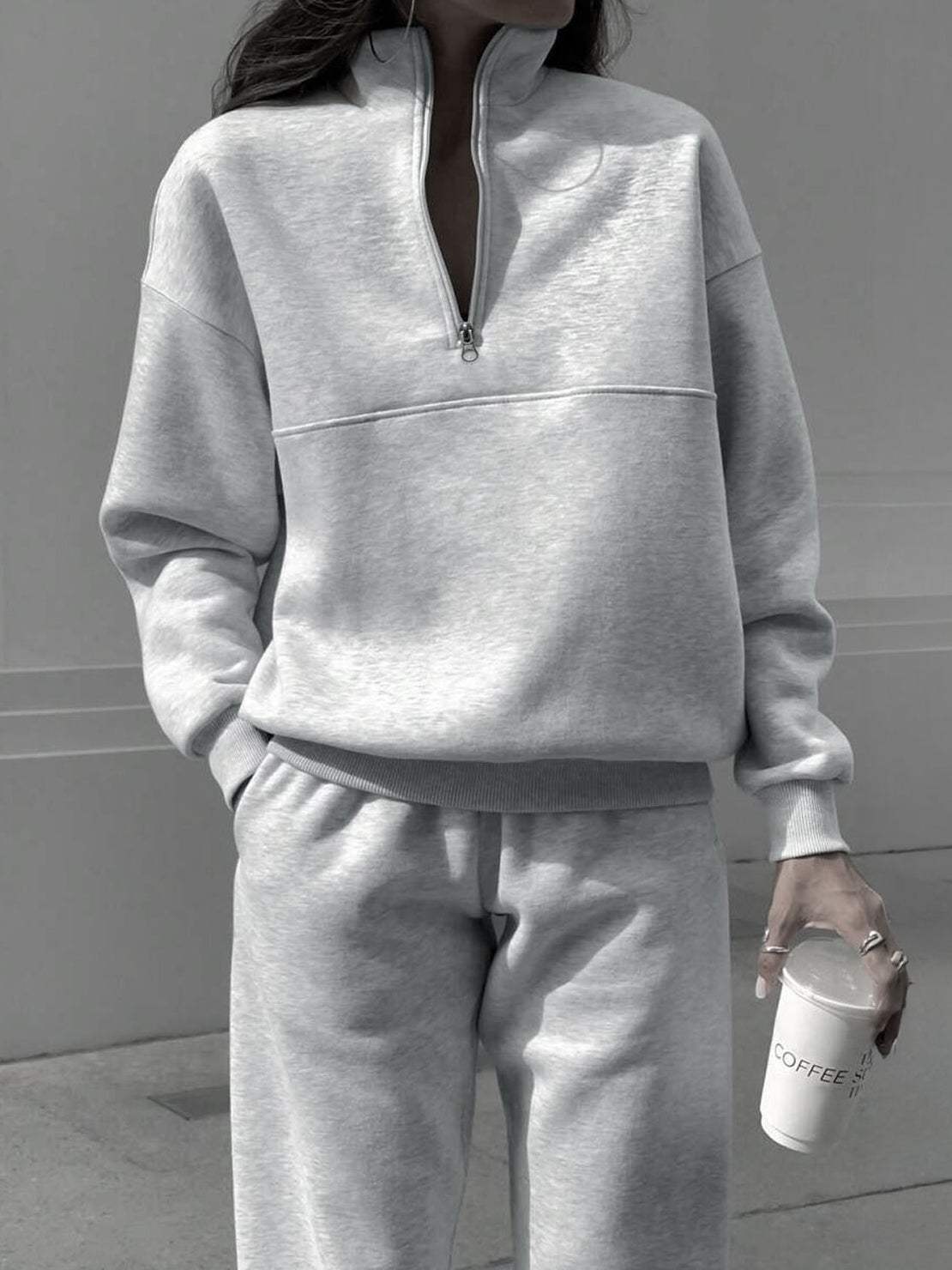 Woman wearing a cotton-blended two-piece tracksuit with high collar and deep zipper in neutral tone