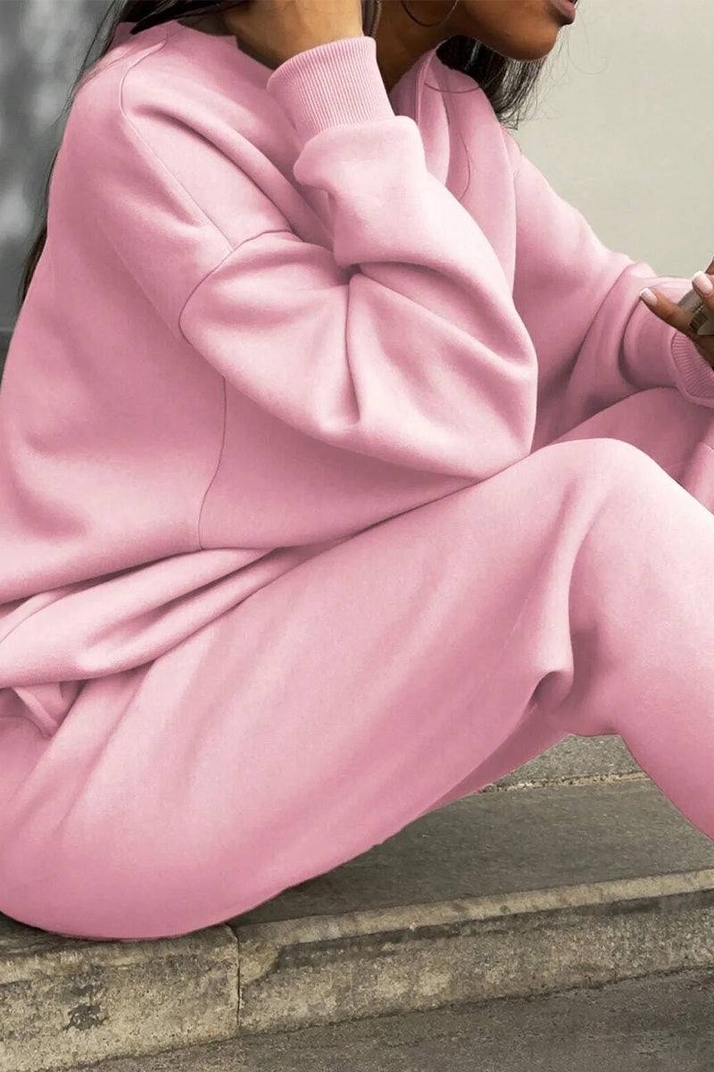 Woman wearing pink Classic Airplane Set two-piece tracksuit with relaxed fit sitting outdoors