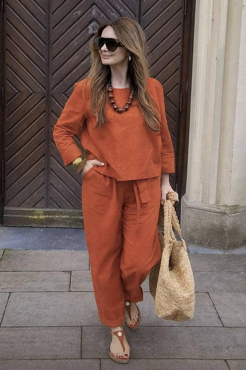 Woman wearing relaxed cotton-linen monochrome capsule outfit in burnt orange with wide-leg pants and longline top.