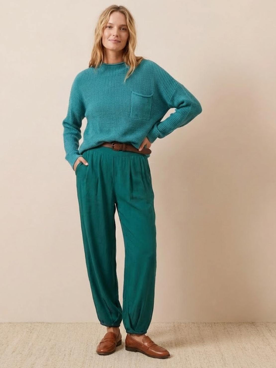 Woman wearing teal relaxed knit sweater and loose trousers embodying European minimalism style