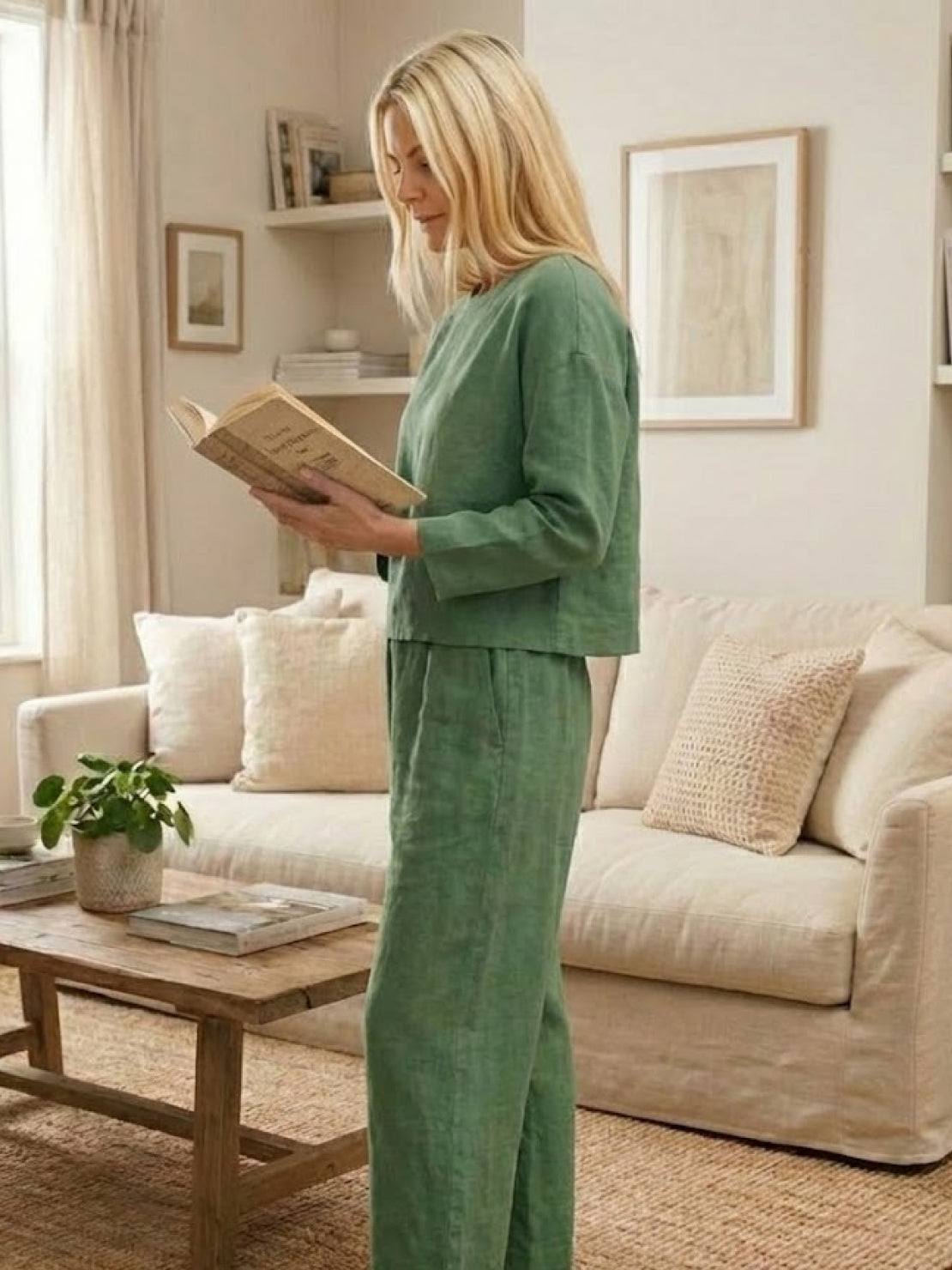 woman wearing loose solid color green two-piece set reading book in cozy living room