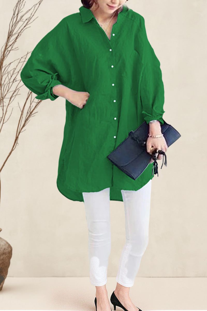 Woman wearing oversized green linen shirt with white pants and black heels, holding a black clutch bag
