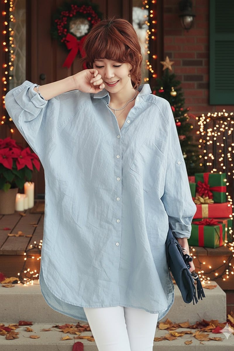 Woman wearing oversized light blue linen shirt with Christmas decorations in background