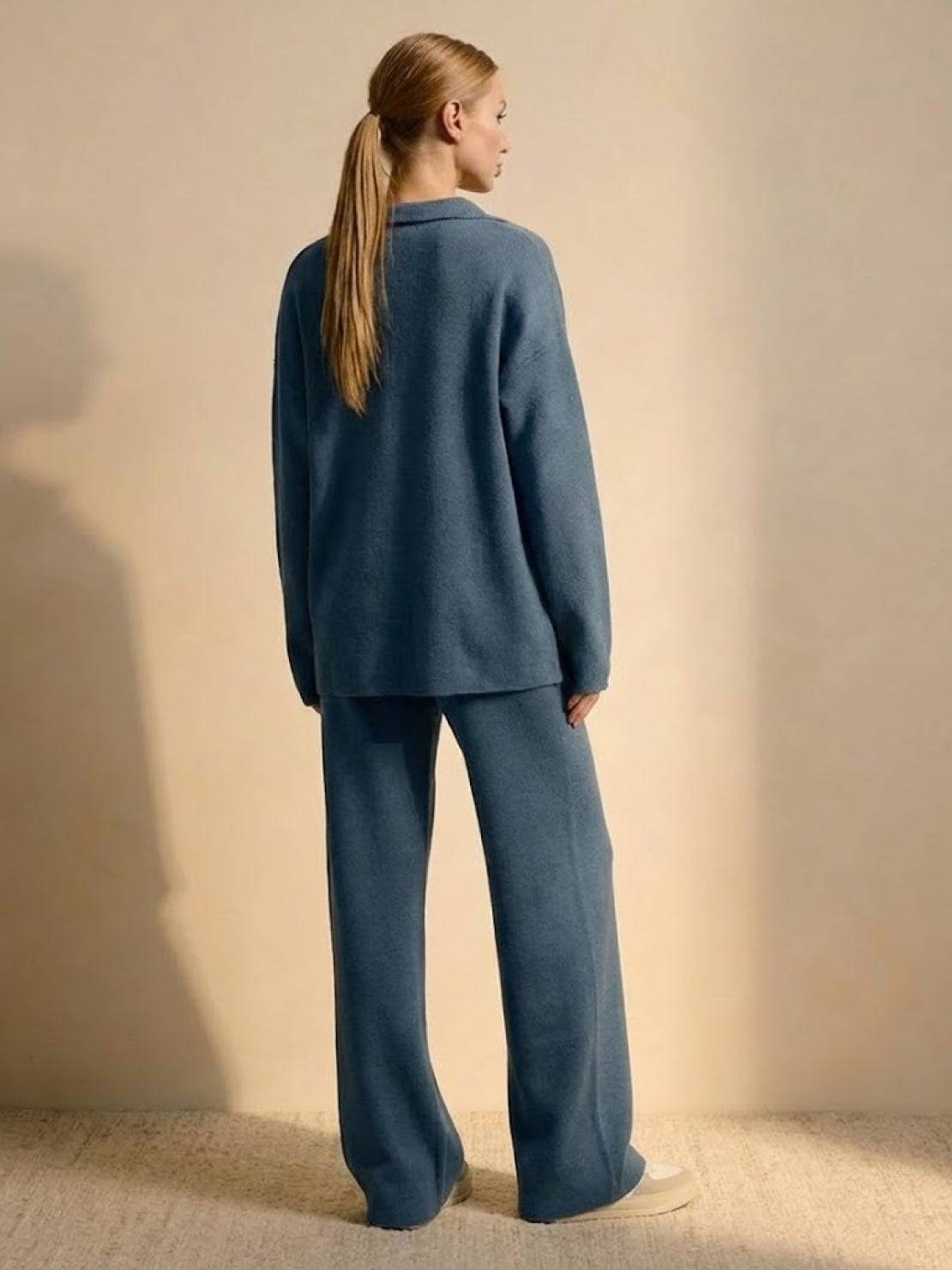 woman wearing plush and preppy camel two-piece set in blue back view standing against beige background