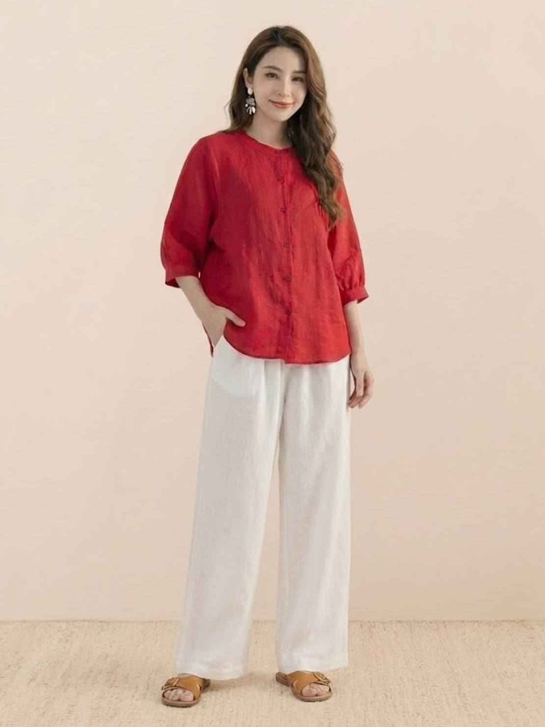 Woman wearing a relaxed loose breathable linen red blouse with white pants and sandals