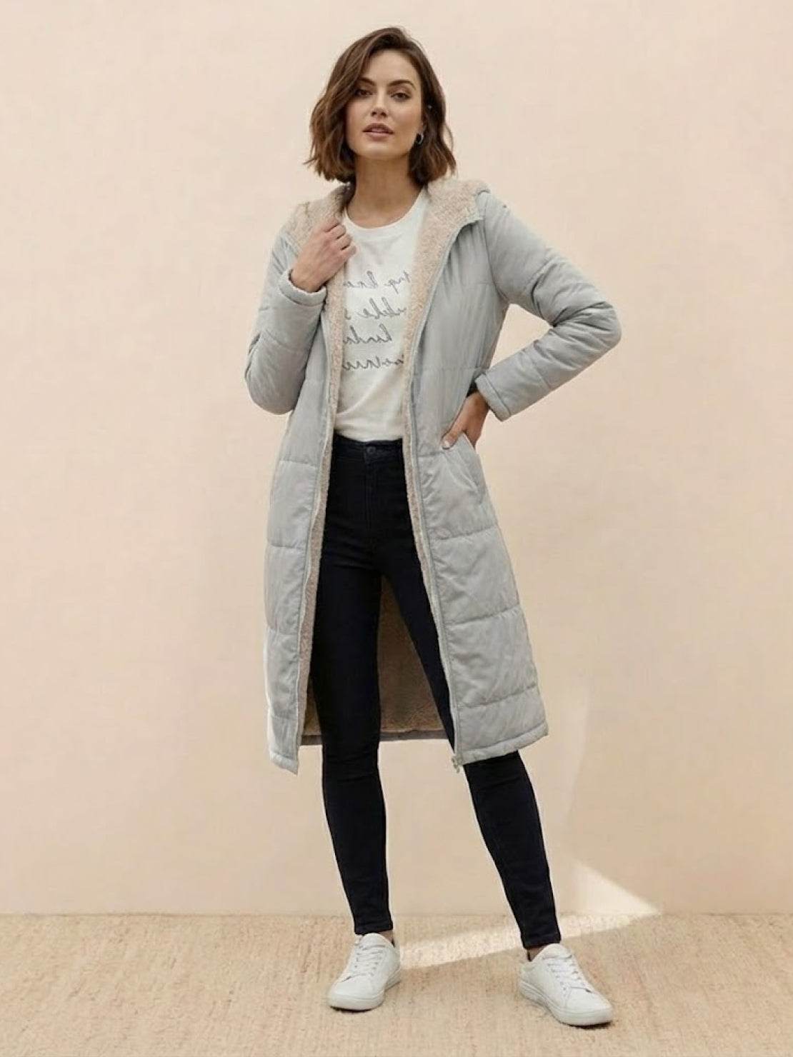 Woman wearing a long gray Sherpa-lined hooded teddy coat over casual outfit