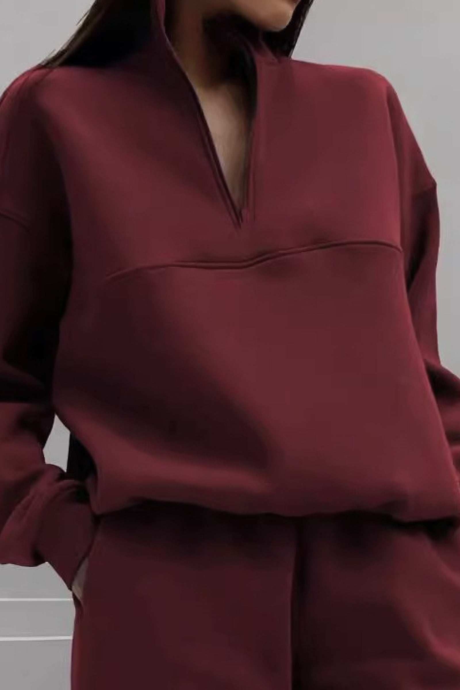Woman wearing a burgundy cotton blend tracksuit with a high collar and zip neckline.