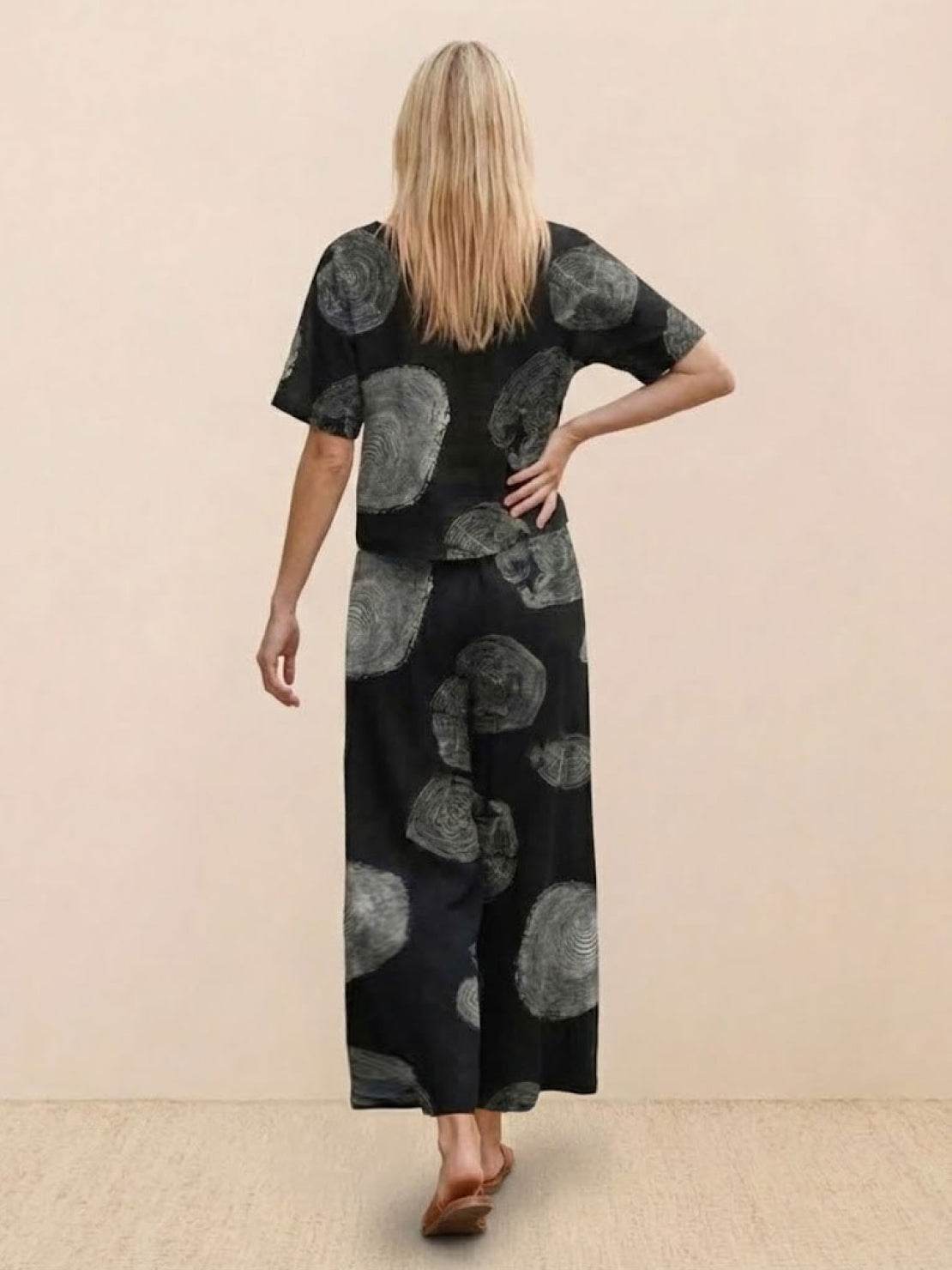 Woman wearing a black loose fit co-ord set with grey abstract floral prints, featuring a relaxed short-sleeve top and wide-leg trousers.