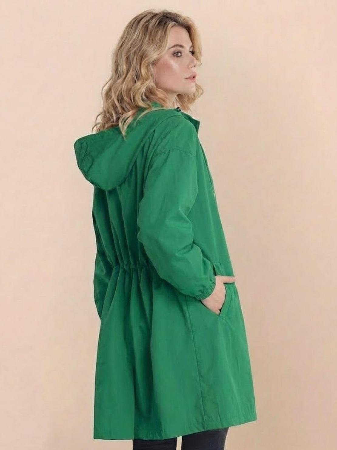 Woman wearing green Rain Couture Windbreaker with oversized fit and hood, side pockets, and adjustable waist