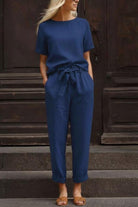 Woman wearing navy blue breathable cotton linen set with relaxed short-sleeve top and straight-leg pants with drawstring waist.