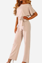 Woman wearing chic short-sleeved wide-leg jumpsuit with belt in light beige color