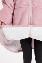 Close-up of oversized ultra soft hooded blanket in pink with white sherpa lining and front zipper detail