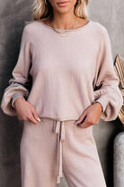 Woman wearing beige round neck loose fit cozy two-piece set with long sleeves and drawstring pants