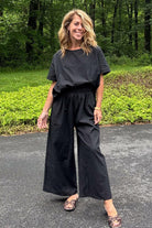Woman wearing black loose fit co-ord set with wide-leg pants and relaxed short sleeve top outdoors