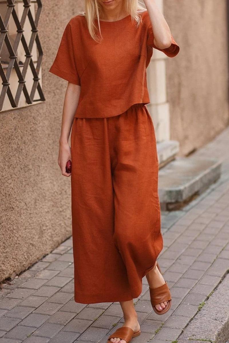 Woman wearing rust-colored loose fit co-ord set with wide-leg trousers and short-sleeve top outdoors