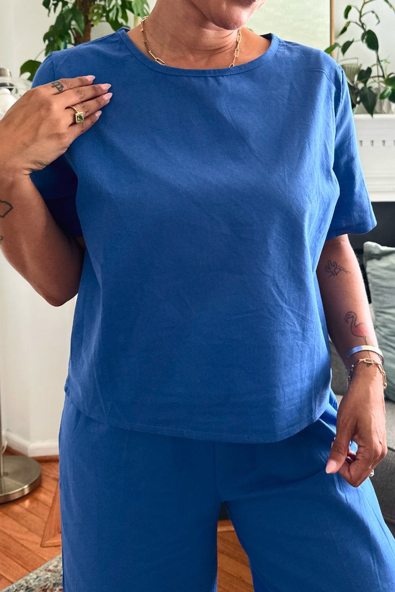 Woman wearing blue loose fit co-ord set with short sleeves and wide-leg pants in casual indoor setting