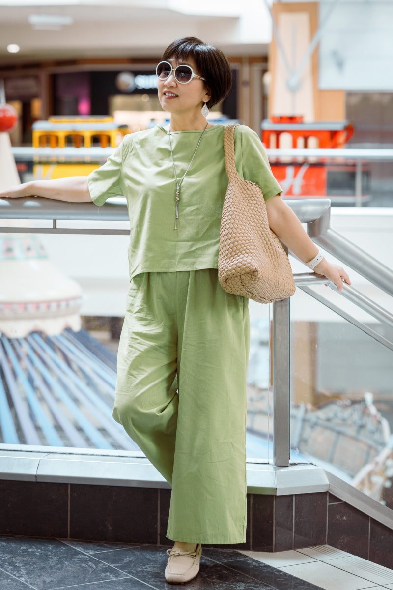 Woman wearing light green loose fit co-ord set with wide-leg pants and short sleeve top in casual urban setting