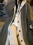 Woman wearing oversized dark gray sherpa coat with buttons, white hoodie, and light pants in urban night setting