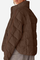 Brown lightweight puffer travel jacket with quilted design and high collar shown from side on model