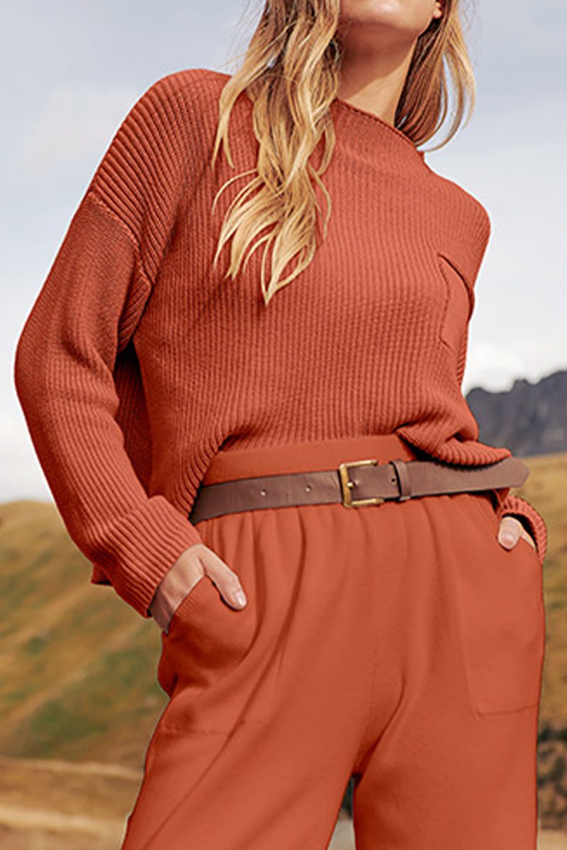 Woman wearing European minimalism relaxed sweater top and trouser set in rust color with brown belt outdoors