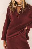 Woman wearing a burgundy oversized two-piece set with a textured knit, featuring long sleeves and button-up collar for multi-weather comfort.