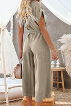 Back view of woman wearing khaki V-neck lace-up pocket jumpsuit with tie and wide legs