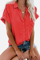 Red V-neck collared button blouse with rolled short sleeves and slim fit worn with denim shorts