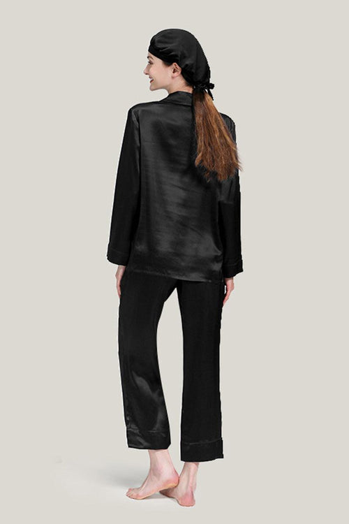Woman wearing black mulberry silk pajama set with matching sleep cap, back view