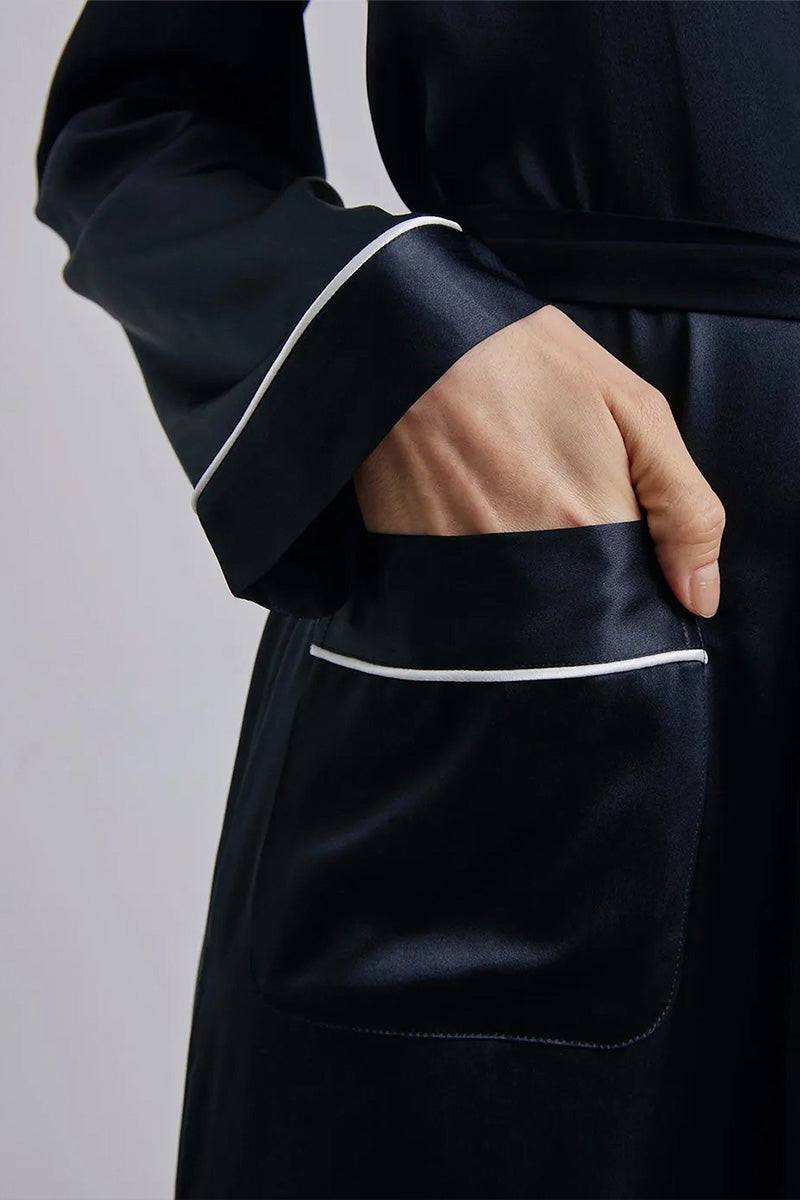 Close-up of a black Mulberry Silk Nightgown with white trim, showing long sleeve cuff, pocket, and sash belt detail.